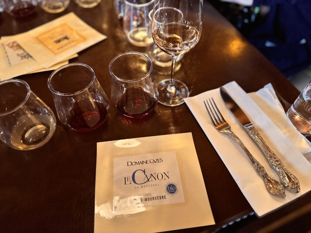東京ディズニーシーのワインプログラムで最後に提供されたロゼワイン「Domaine Cazes」。5杯分のワインとラベル、カトラリーが並ぶペアリング体験の終盤を映した写真。