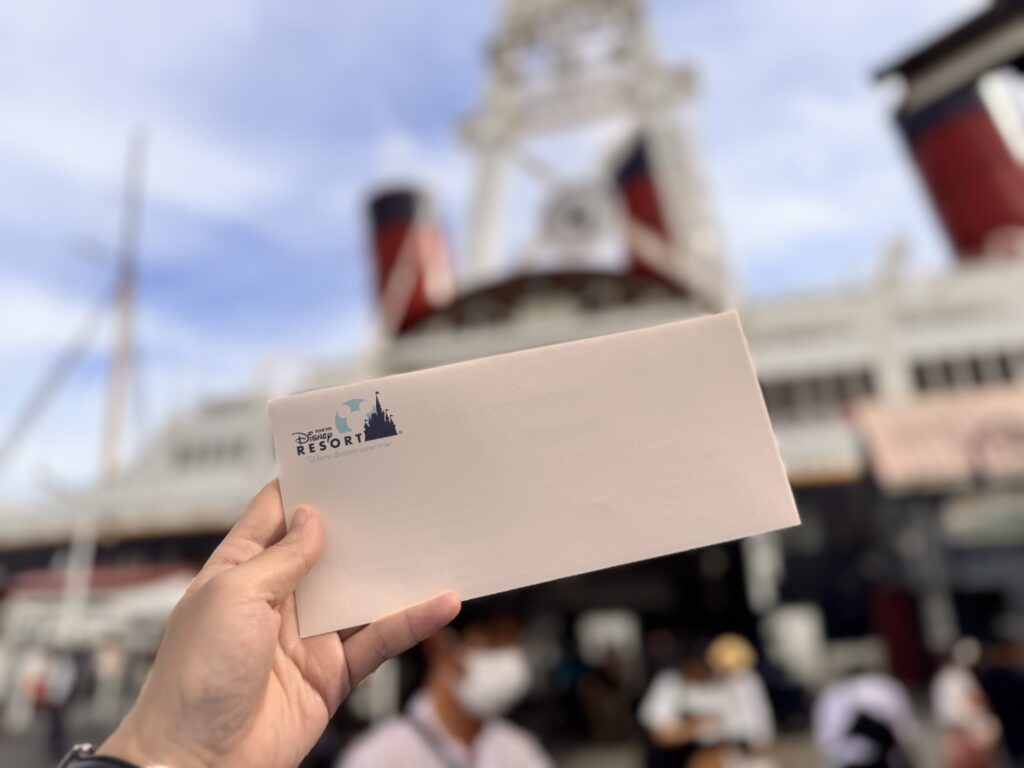 東京ディズニーシーのワインプログラム終了後に出口で渡されたアンケート封筒。背景にはS.S.コロンビア号が写り、イベントの余韻が感じられる一枚。