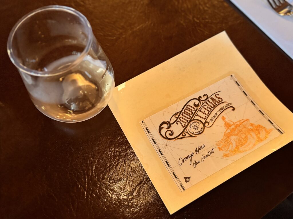 東京ディズニーシーのワインプログラムで提供されたオレンジワイン「20000 LEGUAS」。スキンコンタクト製法で作られた自然派ワインのラベルとグラスが並ぶテーブルの様子。